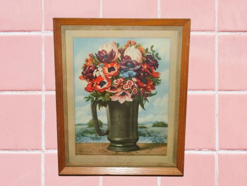 May include: A framed vintage print of a bouquet of colorful flowers in a green ceramic pitcher. The flowers include red, pink, white, and purple blooms. The background is a light blue sky with a green field.