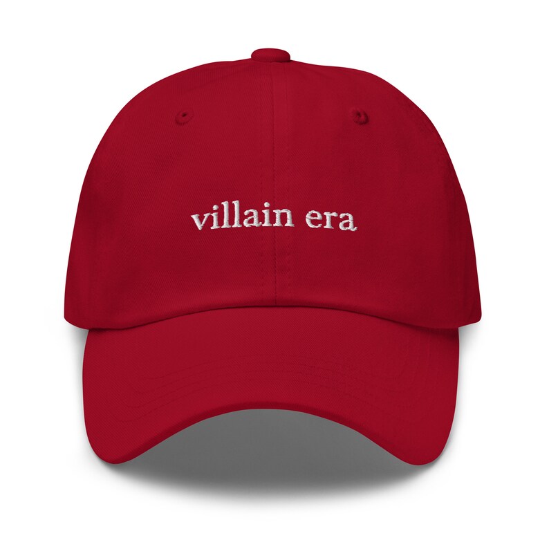 May include: Red baseball cap with white embroidered text that reads "villain era".