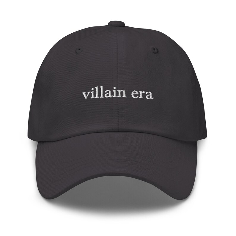 May include: A dark gray baseball cap with the text "villain era" embroidered in white on the front.