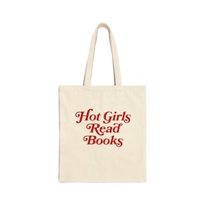 May include: A cream-coloured tote bag featuring the red text "Hot Girls Read Books". The bag has two handles and is made from a durable fabric. Ideal for carrying books and other items, the design is simple and eye-catching.