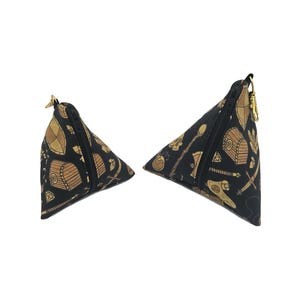 May include: Two black triangular zippered pouches with a gold zipper. The pouches are printed with a pattern of gold treasure chests, swords, and other fantasy items on a black background.