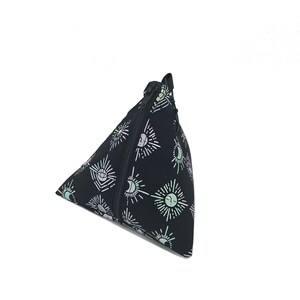 May include: A black triangular zippered pouch with a repeating pattern of white sun and moon symbols. The pouch is made of a soft, fabric material.
