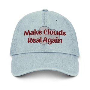 May include: Light blue denim baseball cap with the embroidered phrase "Make Clouds Real Again" in maroon. The text is above a gray cloud graphic. The cap has a curved brim and a button on top.
