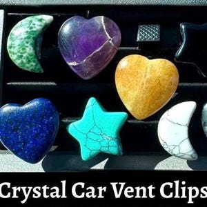 May include: A collection of crystal car vent clips in various shapes and colors, including hearts, stars, and crescent moons. The crystals are in shades of green, purple, gold, blue, turquoise, black, and white. The text "Crystal Car Vent Clips" is displayed at the bottom.