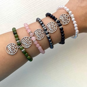 May include: Five bracelets with silver lotus flower charms. The bracelets are made of green jade, pink rose quartz, black onyx, hematite, and white pearls.