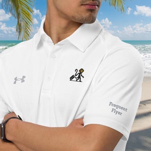May include: White polo shirt with a small monkey graphic and the text "Frequent Flyer" on the sleeve. The Under Armour logo is on the left chest.
