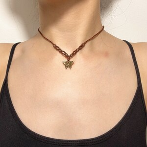 May include: A brown cord choker necklace with a gold butterfly pendant.