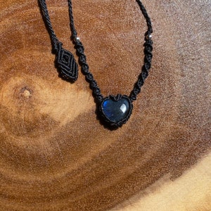 Puede incluir: Un collar de cord&oacute;n negro con un colgante de labradorita en forma de coraz&oacute;n.