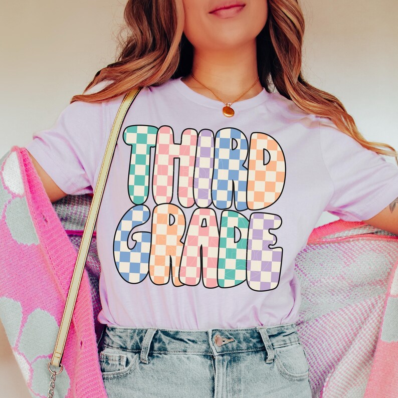 May include: A purple t-shirt with the words "THIRD GRADE" in a colorful checkered pattern.