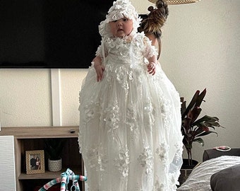May include: A white baby dress with lace and floral embellishments. The dress has a long skirt and a matching bonnet.