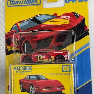 May include: A Matchbox Collectors die-cast toy car set featuring two red Corvette models. The packaging is yellow with the Matchbox logo and the text "04/20". One car is a race car with the number 8, and the other is a 1990 Chevy Corvette ZR1.