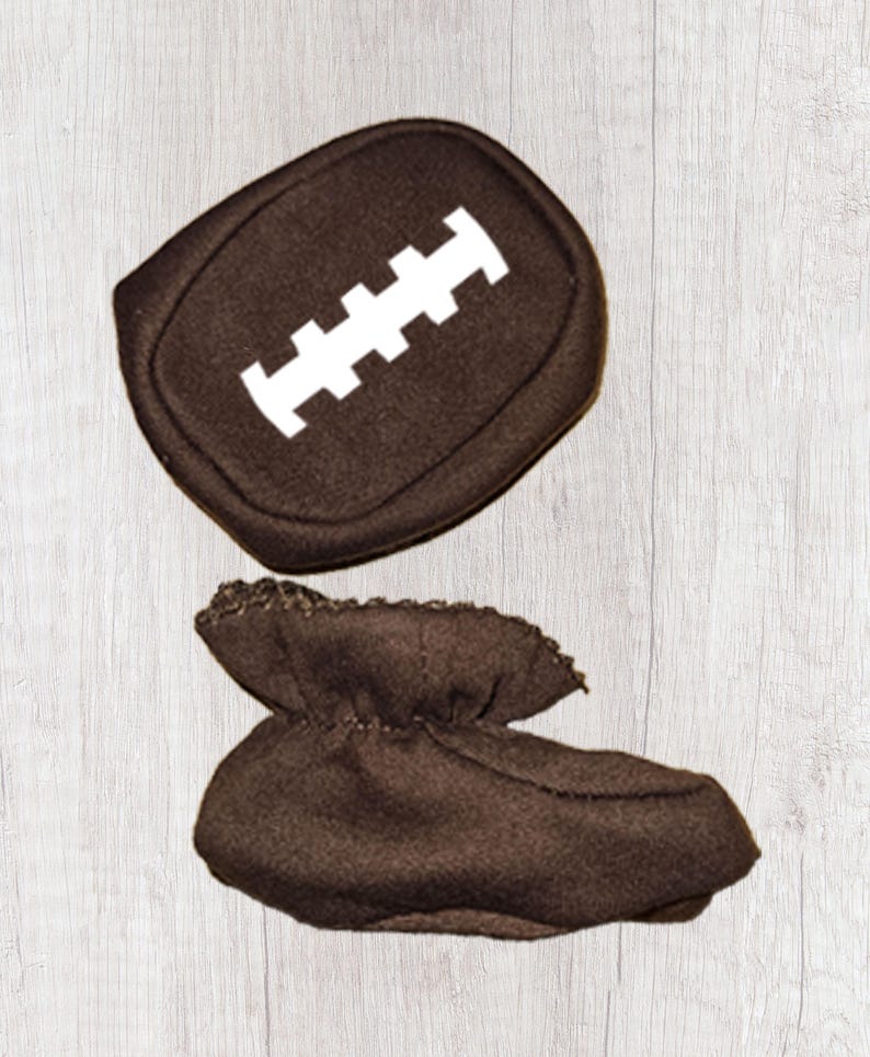 Peut inclure: Bottes de b&eacute;b&eacute; marron et un coussin assorti en forme de ballon de football. Le coussin a un motif cousu blanc. Les chaussons sont faits d'une mati&egrave;re douce et sont con&ccedil;us pour ressembler &agrave; un ballon de football.