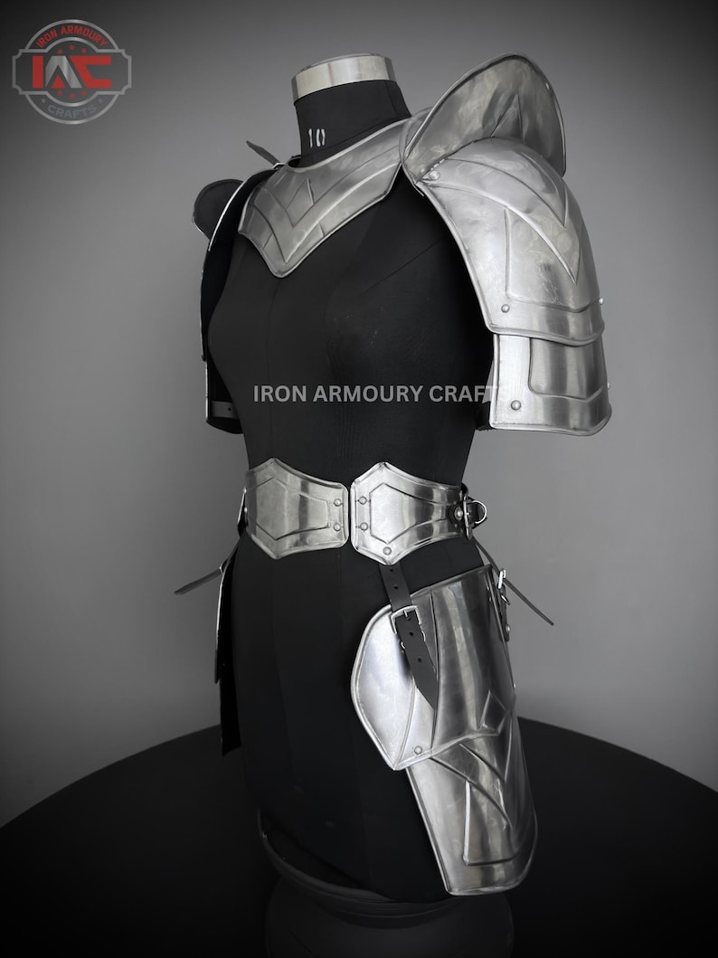 May include: Silver metal armor for the shoulders, waist, and thighs. The armor is made of metal plates and has a sleek, modern design. The armor is displayed on a black mannequin.