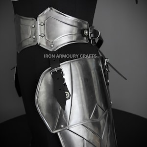 May include: Silver metal armor for the legs and waist. The armor is made of multiple plates and is secured with leather straps. The armor is designed to protect the wearer from injury.