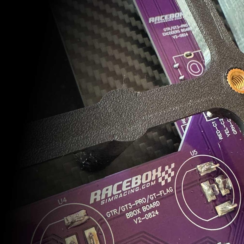A purple circuit board with the text "RACEBOX SIMRACING.COM GTR/GT3-PRO/GT-FLAG BBOX BOARD V2-0824" printed on it. The board has two integrated circuits labeled "U4" and "U5".
