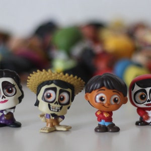 Puede incluir: Un conjunto de ocho pequeñas figuras de plástico de personajes de la película animada Coco. Los personajes incluyen a Miguel, Héctor, Dante, Mamá Imelda y otros. Las figuras son todas de colores brillantes y tienen rasgos detallados.