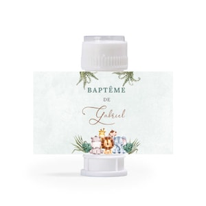 Peut inclure: Une baguette à bulles en plastique blanc avec une carte verte et blanche attachée. La carte porte le texte "BAPTÊME DE Gabriel" et présente une illustration aquarelle d'animaux de la jungle.