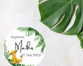 May include: A white circle with a green leafy border and a lion cub illustration. The text "Bapteme Mathis 07 Mai 2023" is written in black.