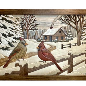 Peut inclure: Œuvre d'art encadrée en bois représentant une scène hivernale avec deux cardinaux perchés sur une clôture enneigée. Un chalet avec une cheminée fumante est à l'arrière-plan. L'œuvre est sculptée et présente diverses nuances de bois.