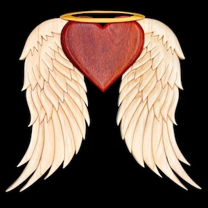 Puede incluir: Un corazón de madera con un halo, rodeado de dos alas de madera talladas. El corazón es rojo y las alas son de color madera claro.