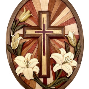 May include: A wooden wall art piece featuring a cross surrounded by lilies. The cross is made of various wood types and has a red center. The lilies are carved in detail and have white petals and green leaves. The background is a radial pattern of different wood types.