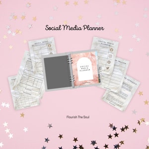 May include: A pink and white marble-patterned social media planner with a ring binder. The planner has a cover that says "Social Media Planner" and "Flourish The Soul".