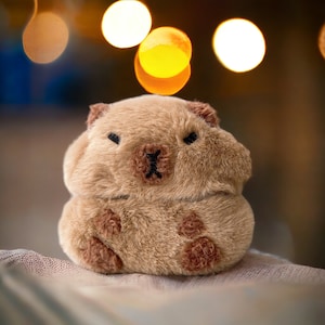 May include: A brown plush toy shaped like a small animal with a round body and a short snout. The toy has black eyes and a small black nose.