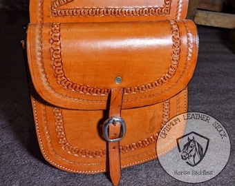 Puede incluir: Un par de alforjas de cuero marrón con costuras intrincadas y un cierre de hebilla. Las alforjas están hechas de cuero de alta calidad y están diseñadas para la durabilidad y la funcionalidad. Optimum Leather Stock Horse Saddles.