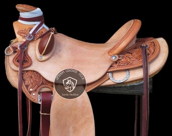 May include: A brown leather saddle with intricate tooling and silver accents. The saddle is made by Optimum Leather Stock, a horse saddle manufacturer.