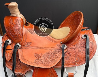 May include: A brown leather saddle with intricate floral tooling. The saddle has a black leather seat and stirrups. The saddle is labeled "Optimum Leather Stock Horse Saddles".