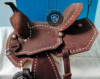 May include: A brown leather horse saddle with white stitching and a silver concho. The saddle is labeled "Optimum Leather Stock Horse Saddles".