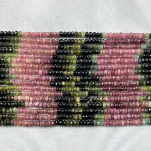 Puede incluir: Una hebra de cuentas de piedras preciosas multicolores. Las cuentas son pequeñas y redondas, y están dispuestas en un patrón repetitivo de rosa, verde, negro y amarillo. Las cuentas están enhebradas en un hilo transparente.