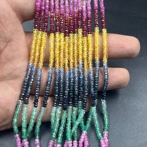 May include: A selection of beaded strands in a variety of colours. The beads are small and round, with colours including green, pink, red, yellow, blue, and black. The strands are held together, displaying the range of colours and textures.