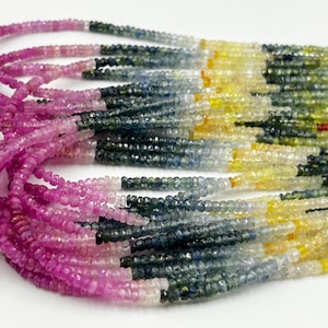 Op de afbeelding: Een meerstrengs ketting met kleine, gefacetteerde, rondelvormige kralen in een levendig kleurverloop. De kralen verlopen van diep magenta en roze naar tinten blauw, geel, groen en eindigen in een helder oranje aan het uiteinde van de strengen.