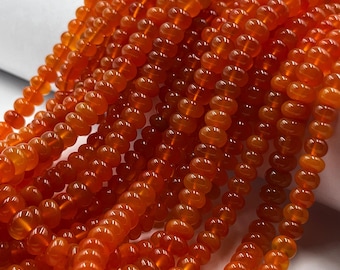 May include: Multiple strands of translucent, round, orange carnelian beads arranged in a cluster. Each bead features a smooth, polished surface with a consistent circular shape, creating a vibrant, warm-toned collection of gemstone jewelry components.