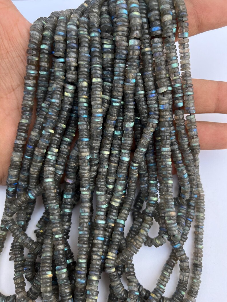 May include: A strand of dark gray labradorite gemstone beads. The beads are faceted and have a shimmering iridescent effect. The beads are approximately 6mm in size.