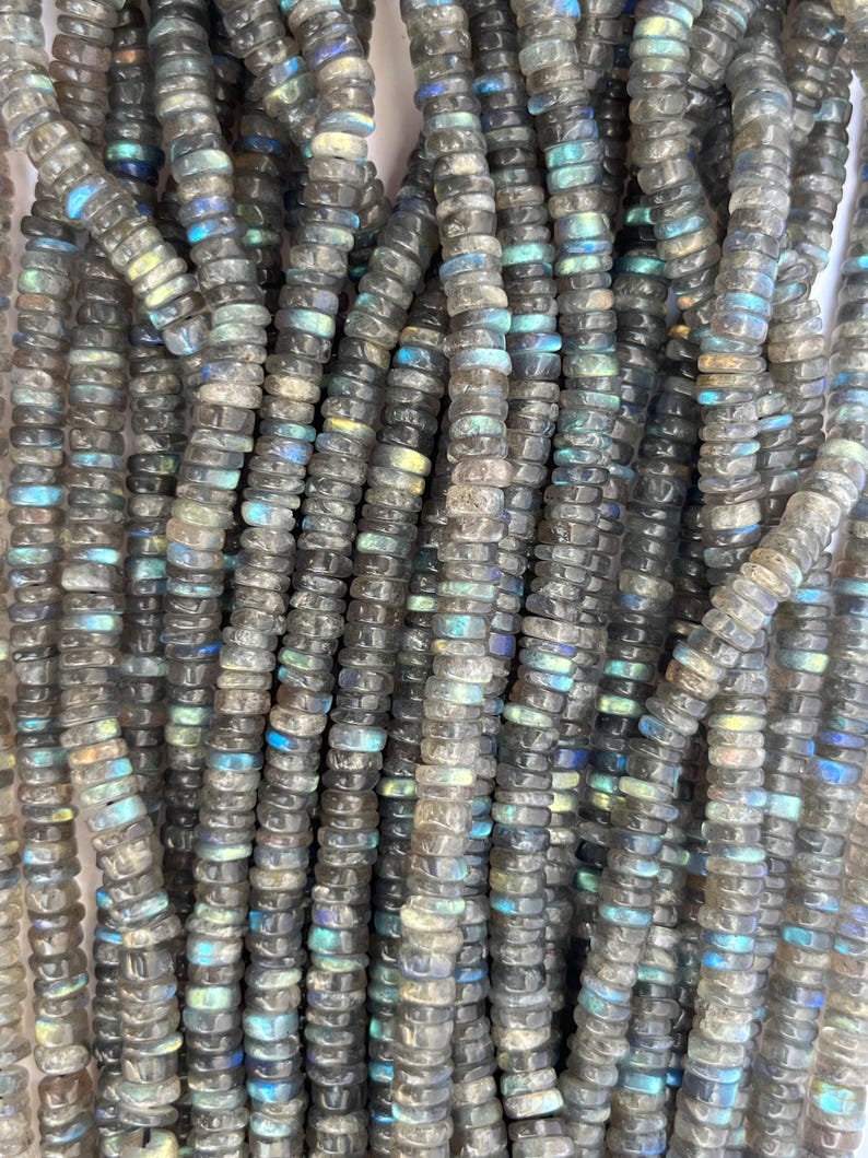 May include: A strand of gray and iridescent labradorite gemstone beads. The beads are small and round, and they have a smooth, polished finish.