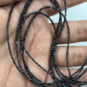 May include: Multiple strands of small, black, faceted beads. The beads are strung together, forming several lines of the same material. The beads have a dark, reflective quality, possibly gemstones or a similar material.