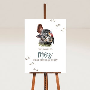 May include: A white welcome sign with a watercolor illustration of a turkey. The sign reads "Welcome to Miles' First Birthday Party".