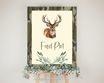 May include: A decorative sign featuring a watercolour illustration of a deer with antlers. The sign reads "Food Plot" in a script font, with a camouflage border. The sign is displayed on a wooden easel.