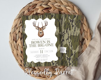 May include: An invitation with a deer illustration, the text "Bowen is the Big One", and event details. The background features a camouflage pattern. The invitation is on a woven placemat.