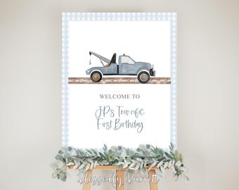 May include: A blue and white welcome sign with a blue tow truck illustration and the text "Welcome to JP's Tour-rific First Birthday".