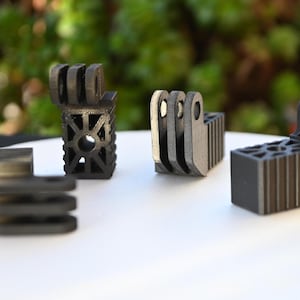 Puede incluir: Cuatro soportes de cámara GoPro impresos en 3D de color negro. Los soportes son de diferentes formas y tamaños.