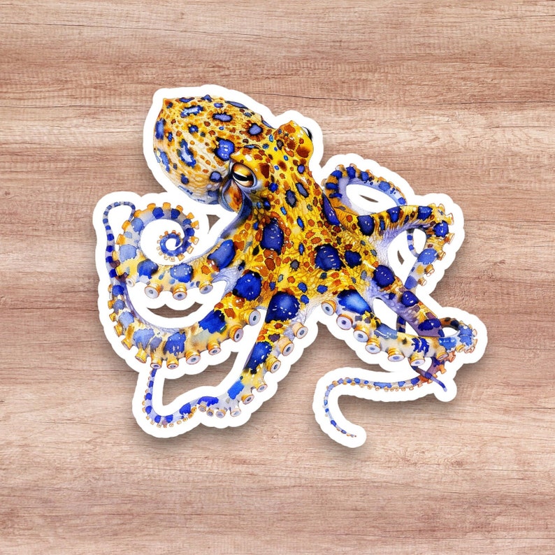 May include: A blue ringed octopus sticker with yellow and blue spots. The octopus has eight tentacles with suckers. The sticker is on a wood background.