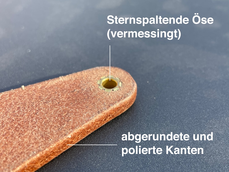 May include: Close-up of a brown leather strap with a brass star-shaped eyelet. The eyelet has rounded and polished edges. The text "Sternspaltende &Ouml;se (vermessingt)" is visible above the eyelet.