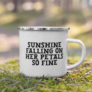 May include: White enamel camping mug with a black inscription that reads "Sunshine falling on her petals so fine".