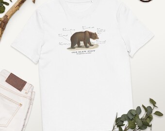 May include: White t-shirt with a brown bear illustration and the text "OLE SLEW FOOT" and "Scientific reader".
