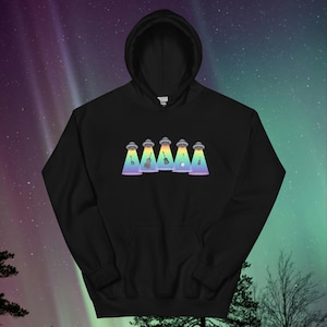 Puede incluir: Sudadera con capucha negra con un gráfico de cinco ovnis con luces de arcoíris que brillan sobre instrumentos musicales, incluyendo una guitarra, un violín, un violonchelo y un banjo.