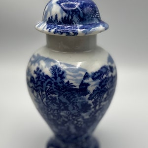 Puede incluir: Un pequeño jarrón de porcelana azul y blanco con tapa. El jarrón tiene un diseño floral y un estilo chino tradicional.