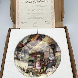 May include: A Royal Doulton collector's plate from the Old Country Crafts series, featuring a cottage with a thatched roof and a woman spinning wool. The plate is titled "The Spinner" and is numbered 13949.
